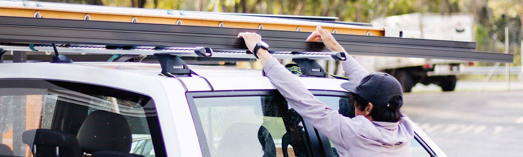 man reaching for ladder on top of a ute